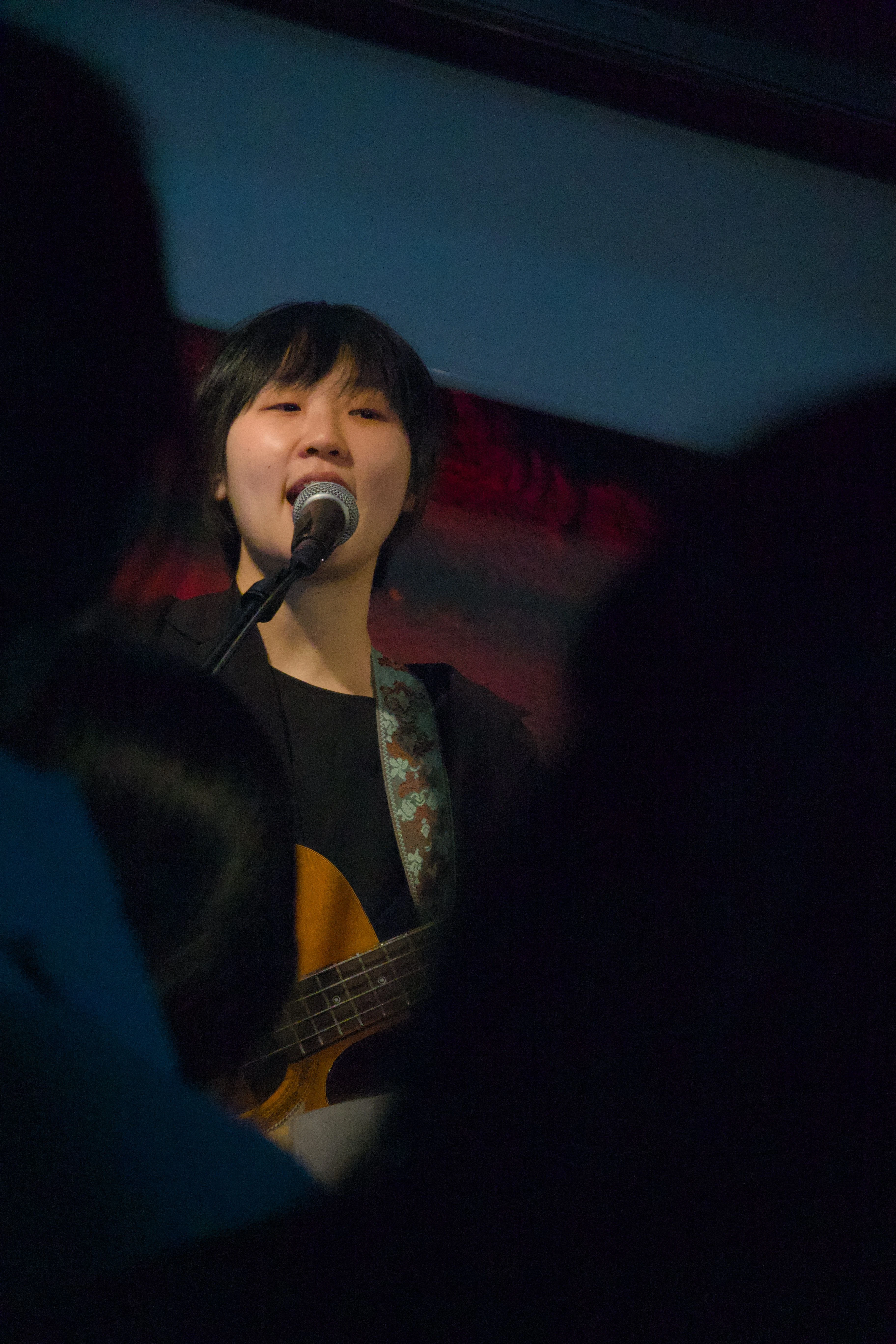 관객석을 바라보면서 베이스 기타를 연주하며 노래를 부르는 싱어송라이터 우희준의 모습.