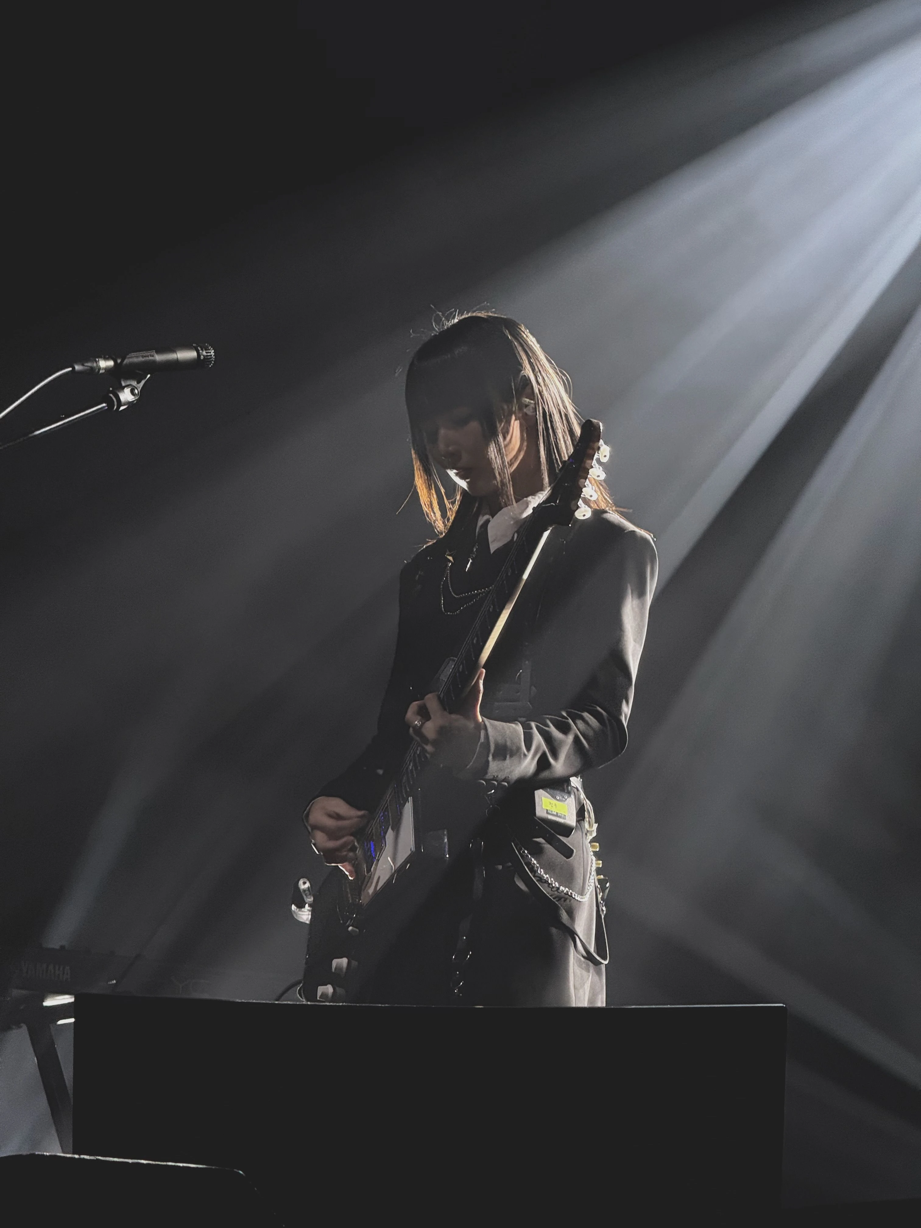 가수 정우가 무대에서 일렉트릭 기타를 연주하고 있다. 무대 조명은 그의 뒷모습을 위에서 비추고 있다.