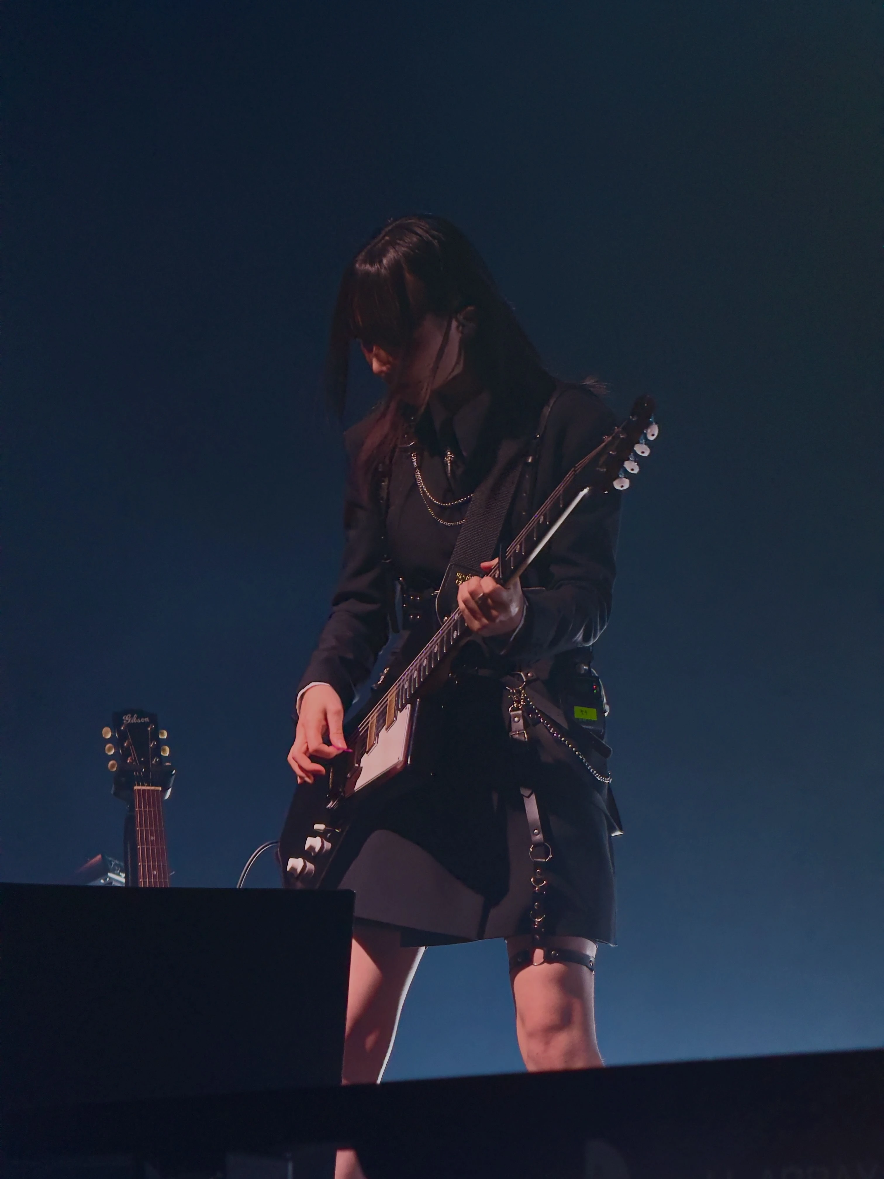 가수 정우가 무대에서 시선을 아래로 향한 채로 일렉트릭 기타를 연주하고 있다.