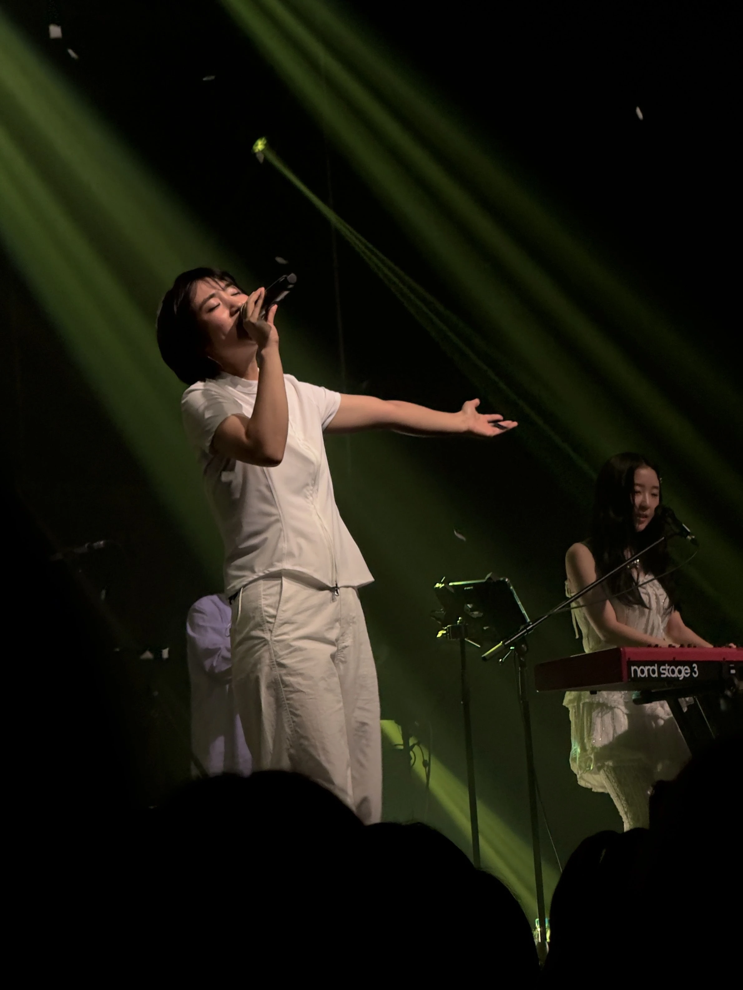 신온유가 오른손에 마이크를 쥐고 노래를 부르면서 왼팔을 옆으로 뻗고 있다. 그의 옆에는 키보드를 연주하는 하형언의 모습이 보인다.