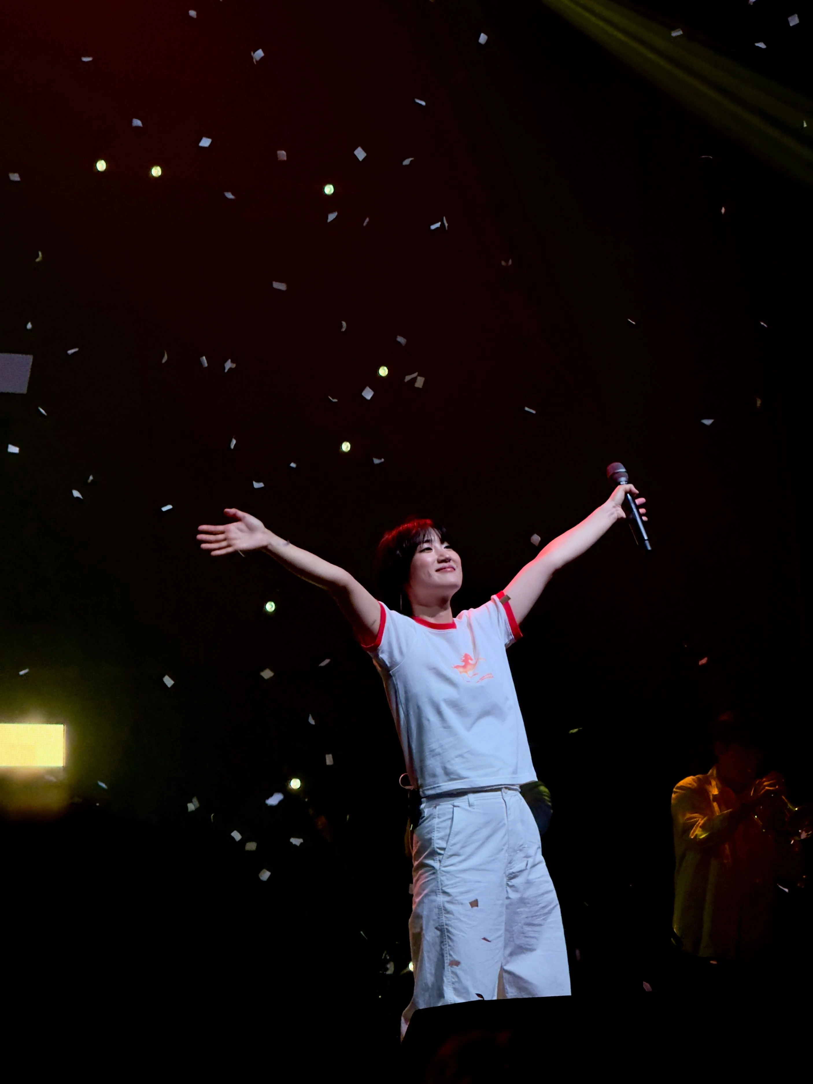 신온유가 관객석을 바라보며 팔을 양옆으로 뻗고 있다. 무대 위에는 컨페티가 떨어지고 있다.