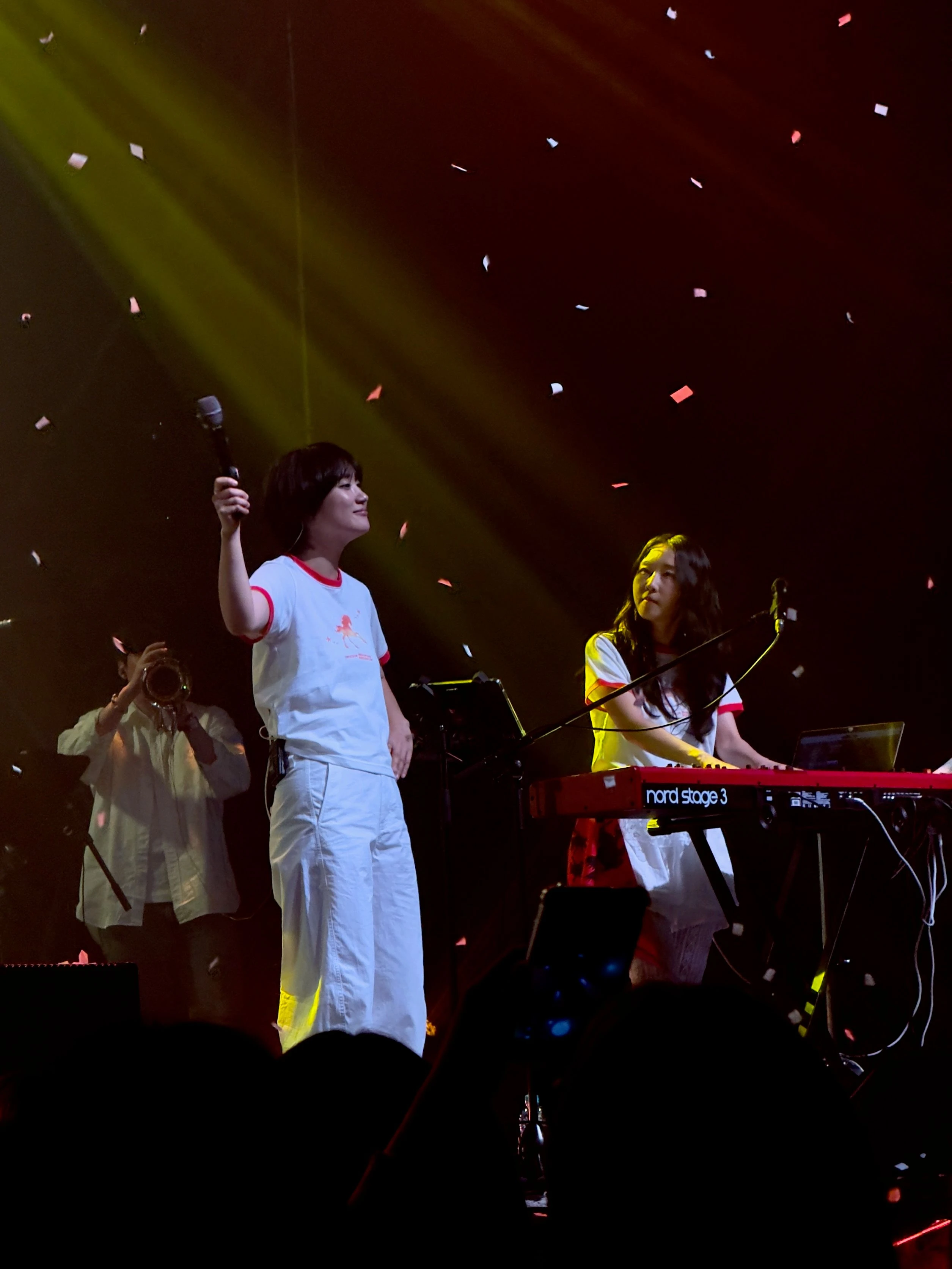 무대 위에서 떨어지는 컨페티 아래 신온유가 마이크를 잡고 위를 향해 들고 있고, 하형언은 키보드를 연주하며 신온유의 모습을 바라보고 있다.