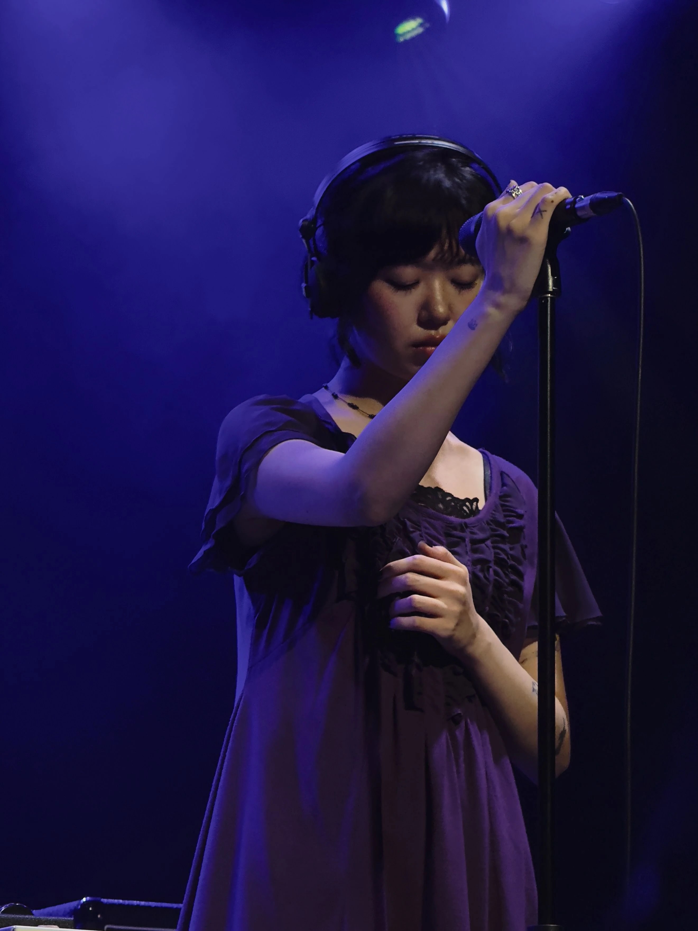 윤지영이 스탠드에 장착된 마이크를 잡으며 눈을 감고 있다.
