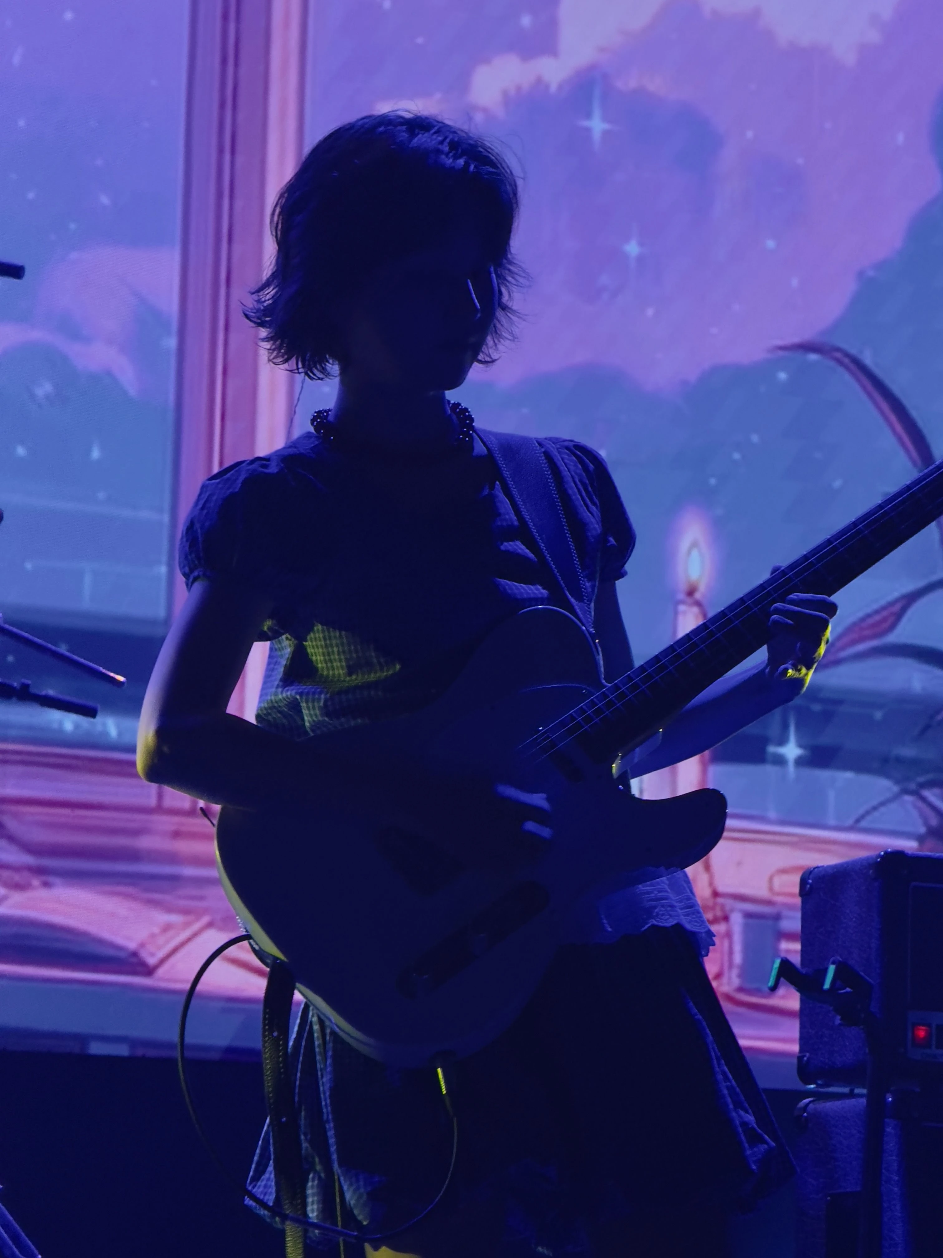 김수영이 일렉트릭 기타를 연주하고 있다. 조명은 그의 뒷모습을 은은하게 비추고 있다.