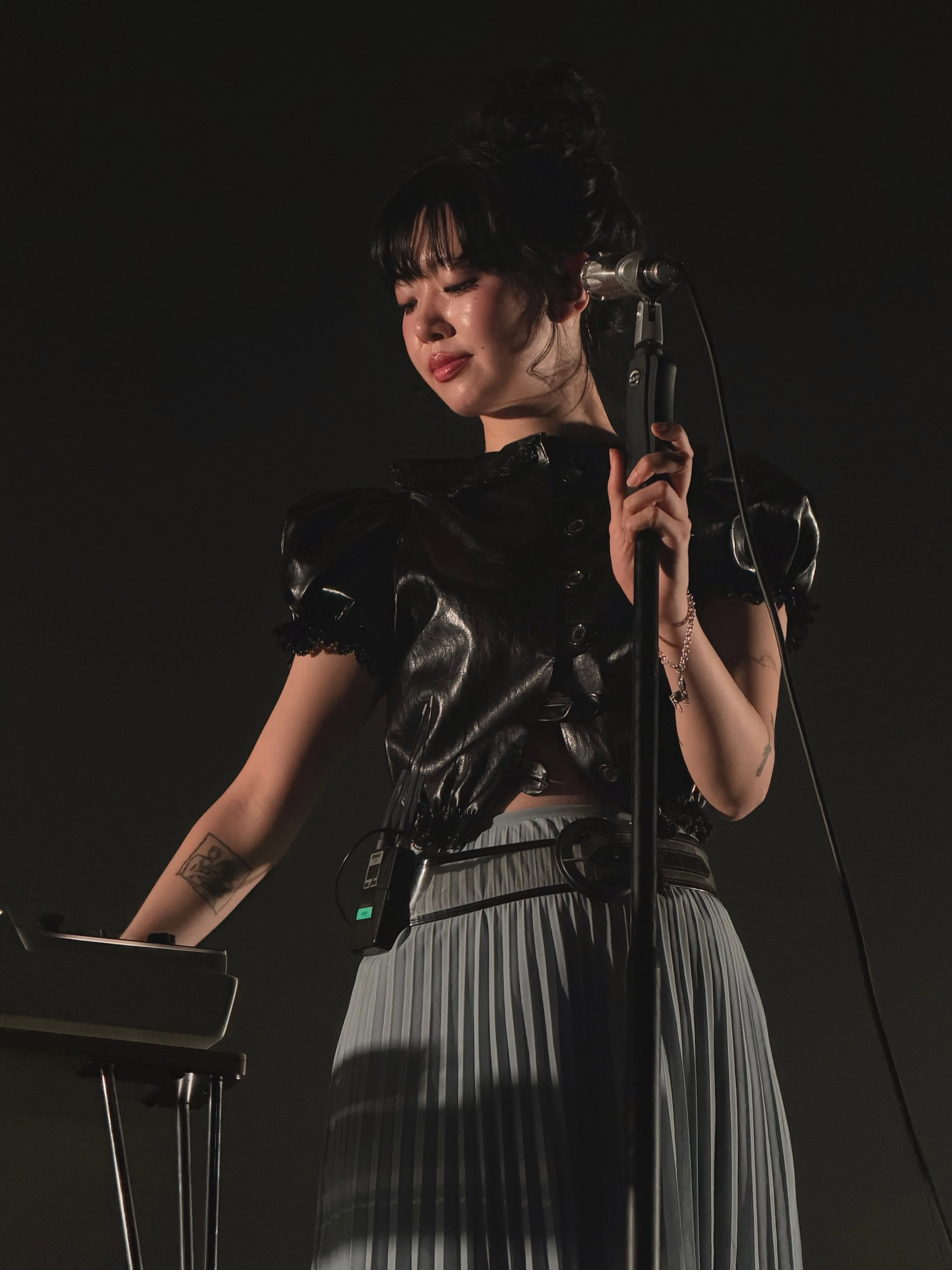 마이크 스탠드를 잡고 그의 오른편에 있는 키보드를 바라보며 연주하는 윤지영의 모습.