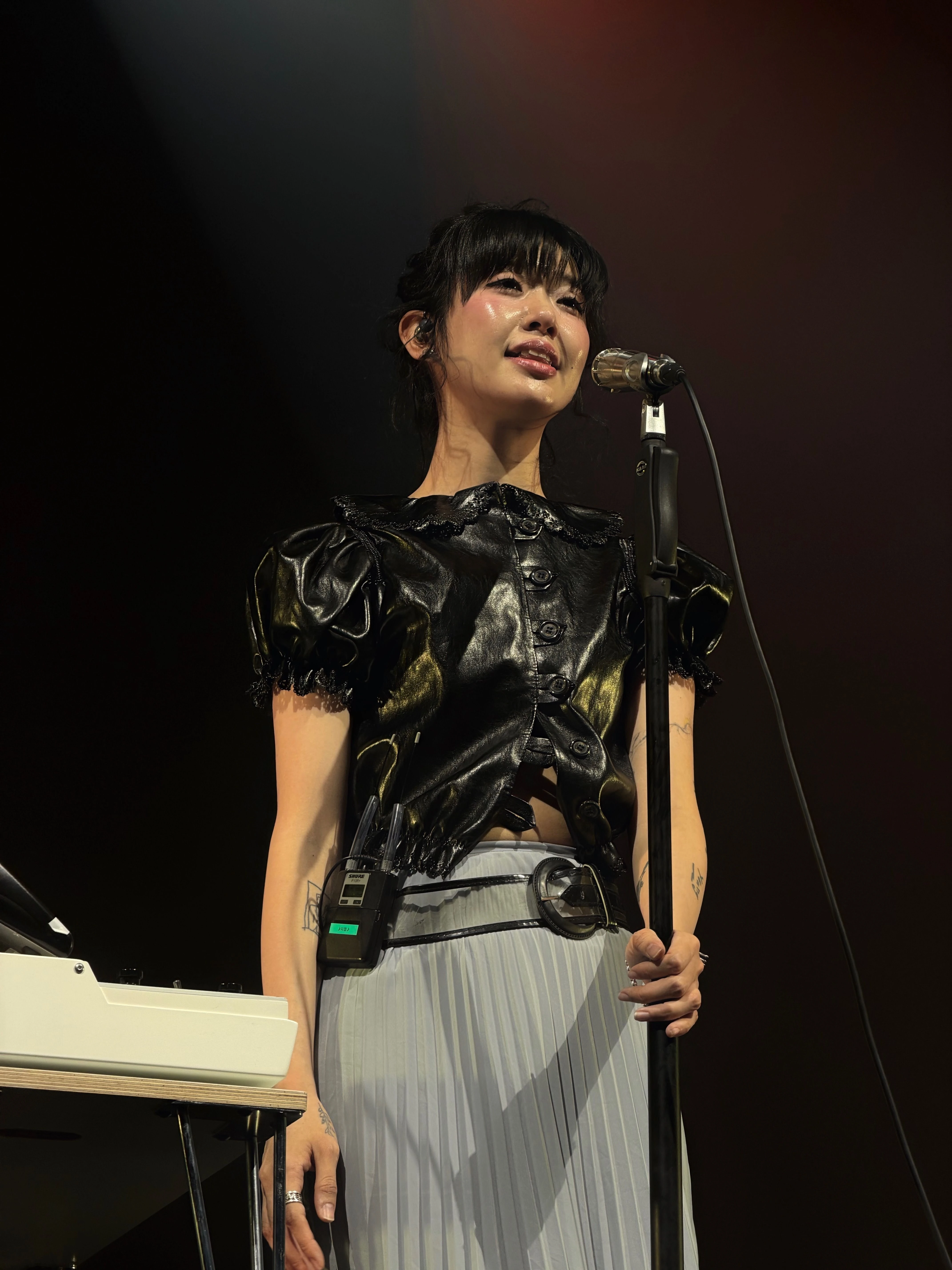 마이크 스탠드를 잡으며 관객석을 바라보고 노래를 부르는 윤지영의 모습.