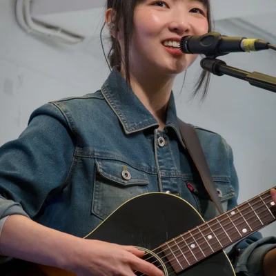 어쿠스틱 기타를 연주하면서 노래를 부르는 싱어송라이터 정우의 모습. 관객석을 바라보며 웃음을 짓고 있다.