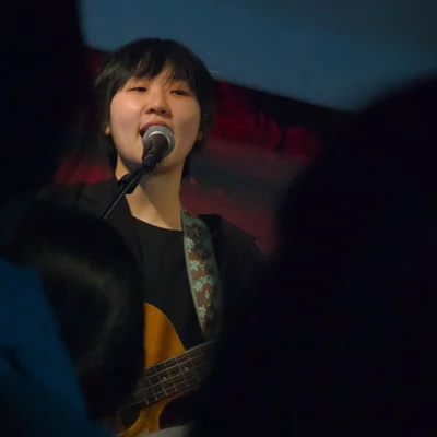 관객석을 바라보면서 베이스 기타를 연주하며 노래를 부르는 싱어송라이터 우희준의 모습.