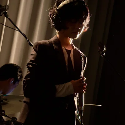 가수 윤지영이 마이크를 잡으며 눈을 감고 있다. 무대 조명은 그의 측면을 비추고 있다.