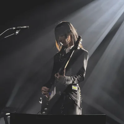 가수 정우가 무대에서 일렉트릭 기타를 연주하고 있다. 무대 조명은 그의 뒷모습을 위에서 비추고 있다.