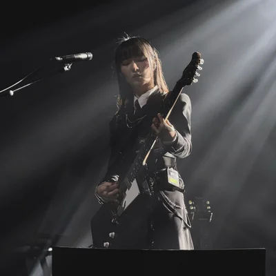 가수 정우가 무대에서 일렉트릭 기타를 연주하고 있다. 무대 조명은 그의 측면을 위에서 비추고 있다.