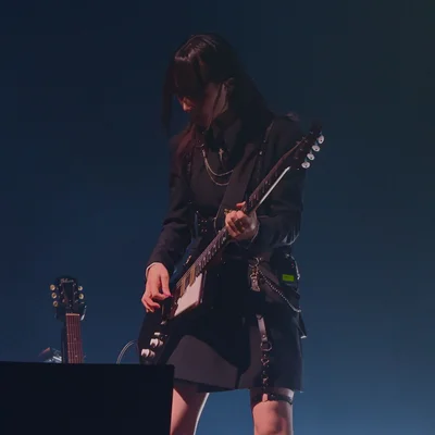 가수 정우가 무대에서 시선을 아래로 향한 채로 일렉트릭 기타를 연주하고 있다.