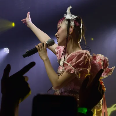 롤리타 패션 복장을 한 WEDNESDAY CAMPANELLA(수요일의 캄파넬라)의 우타하가 왼손에 마이크를 잡은 채로 오른손을 권총 모양으로 만들어 팔을 뻗고 있다. 객석에는 우타하의 오른손을 따라하는 관객들의 손이 보인다.