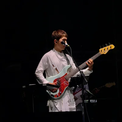 신인류의 문정환이 마이크 스탠드 앞에서 일렉트릭 베이스 기타를 연주하고 있는 모습.