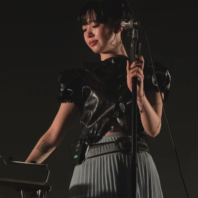 마이크 스탠드를 잡고 그의 오른편에 있는 키보드를 바라보며 연주하는 윤지영의 모습.