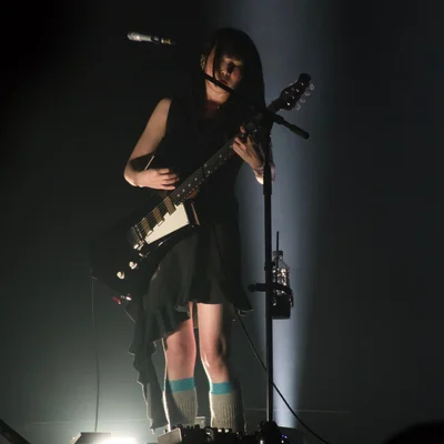 일렉트릭 기타를 연주하는 정우의 모습. 흰색 조명이 무대 아래에서 그를 비춘다.